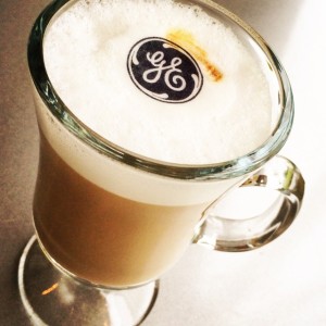 General Electric logo featured on a Beverage Topper which is floating on a cappuccino exclusively by Espresso Dave Coffee Catering