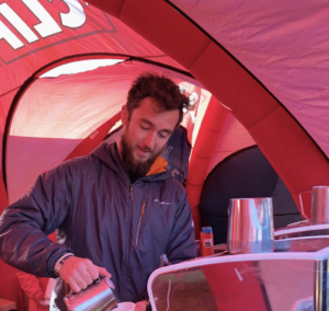 Barista in a red tent pouring steamed milk