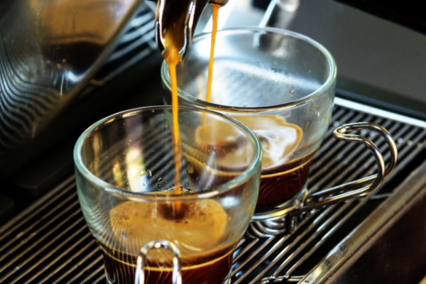 Fresh espresso being pulled into two short glass cups with handles