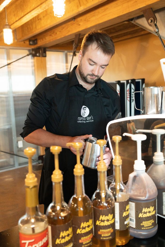 An Espresso Dave barista prepares drinks at a mobile espresso cart, showcasing what makes coffee sustainable through personalized service and ethically sourced ingredients.