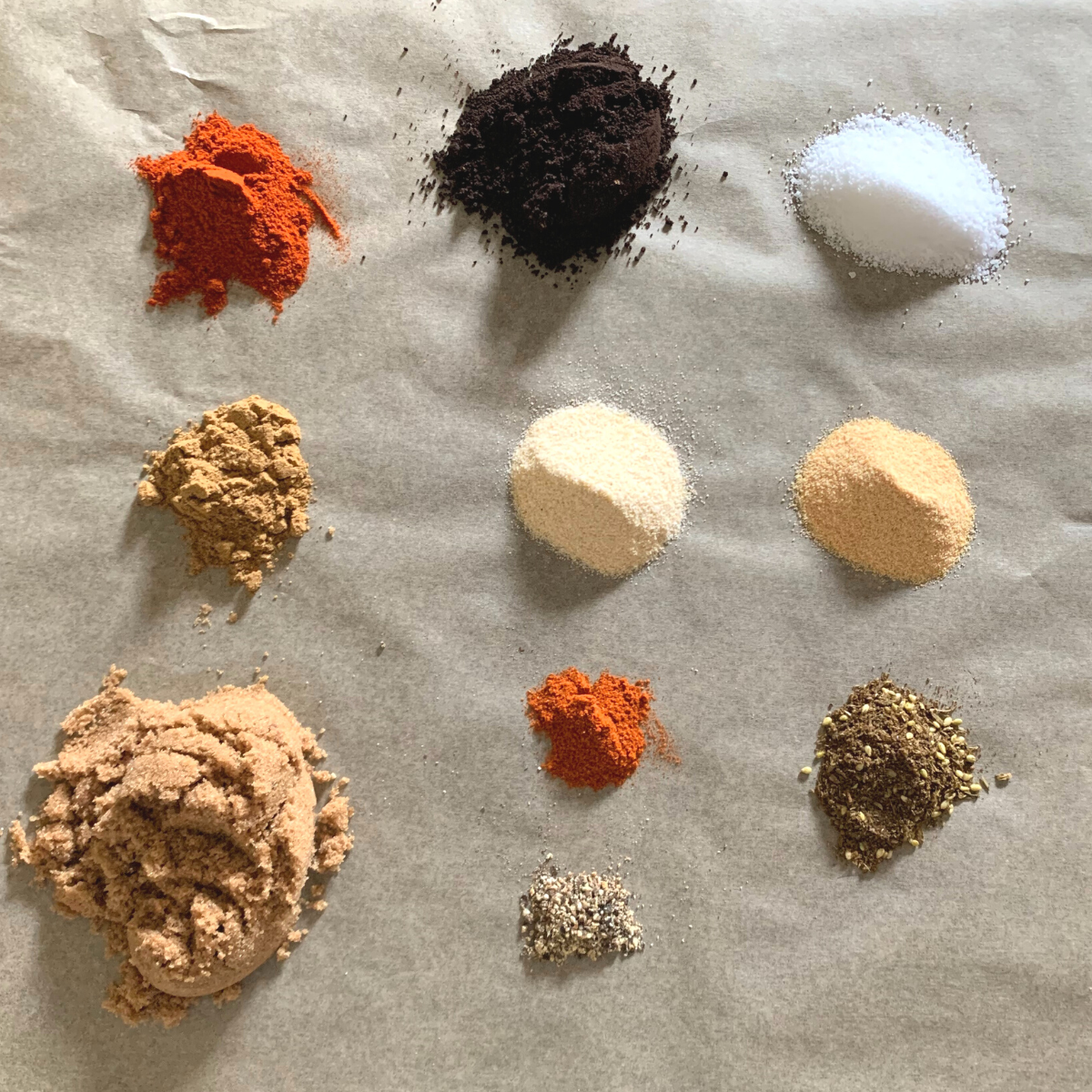 Flatlay of dry rub spices including ground coffee, paprika, sugar, and seasonings used in coffee spice dry rub recipe for grilling