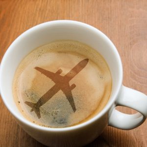 A cup of espresso with an airplane silhouette in the foam, illustrating the question “Is airplane coffee safe to drink?” from Espresso Dave’s Coffee Catering blog.