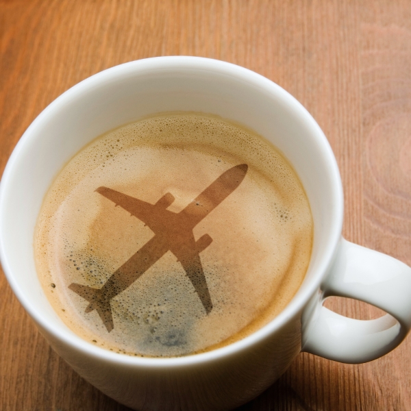 A cup of espresso with an airplane silhouette in the foam, illustrating the question “Is airplane coffee safe to drink?” from Espresso Dave’s Coffee Catering blog.