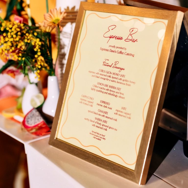 Framed Espresso Bar menu on a counter with a floral arrangement blurred in the background, warm lighting.